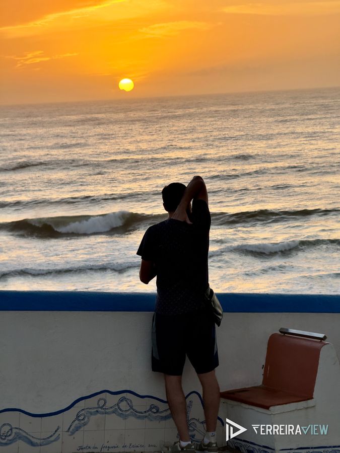 Fotógrafo de costas ao pôr do sol num miradouro da Ericeira